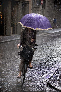 Rain in Florence, woman on bicycle with umbrella